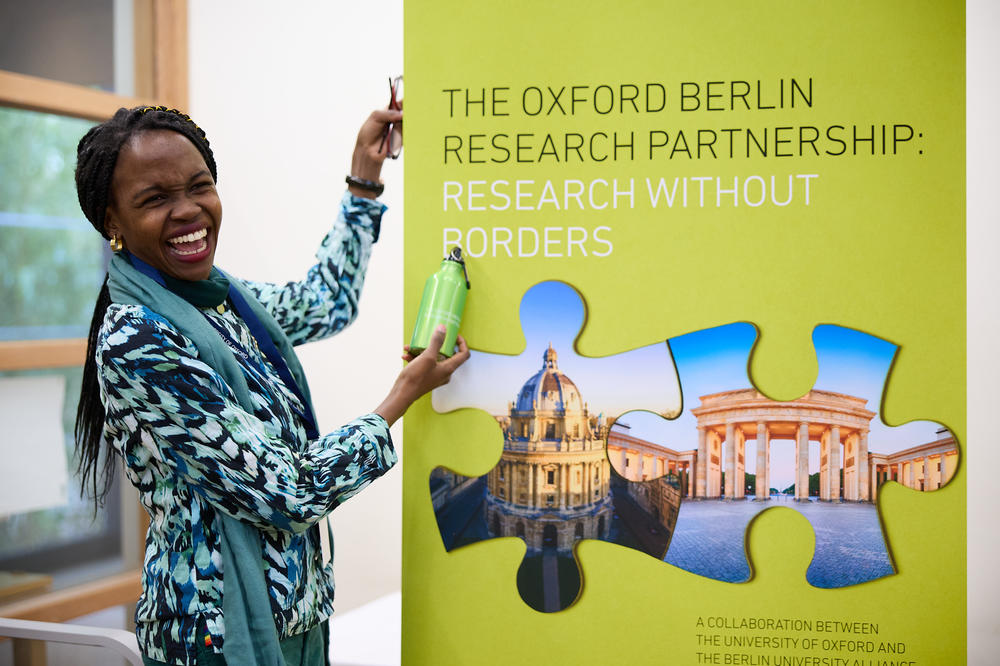 Eine Konferenzteilnehmerin neben dem Plakat der Oxford Berlin Research Partnership