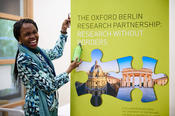 A conference participant next to the banner of the Oxford Berlin Research Partnership