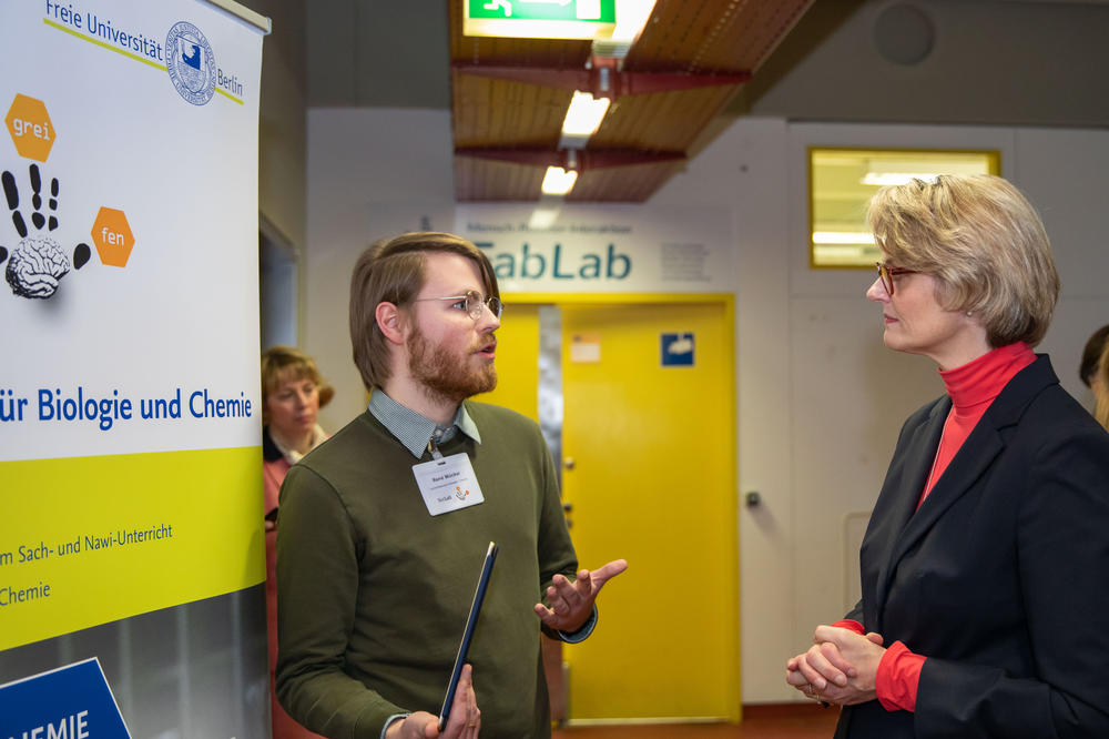 Teaching student René Muckai explains to Minister Karliczek the digital teaching and learning concept he developed that school classes can use to prepare their student lab visits.